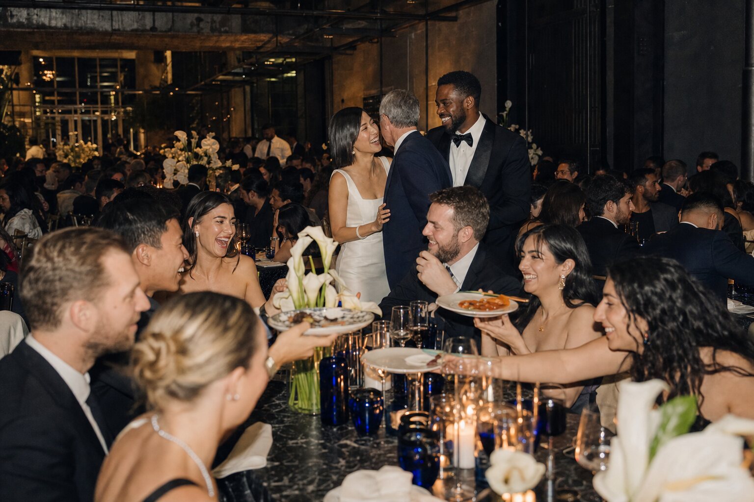 Wedding guests sharing dinner and conversation around a candlelit table